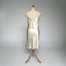Load image into Gallery viewer, A silk satin slip dress in ivory color, displayed on a mannequin against a neutral gray studio background.
