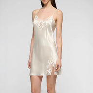 Woman wearing an ivory pure silk satin slip dress with lace details on a plain background.