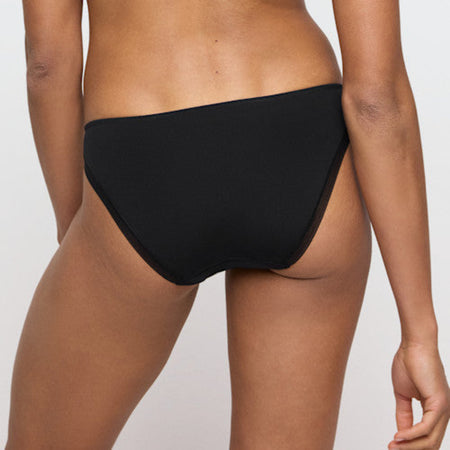 Black bikini bottom worn by a person on a plain background