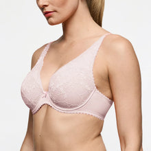Load image into Gallery viewer, A close-up of a woman wearing a light pink lace underwire bra against a plain light gray studio background.
