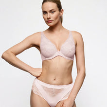 Load image into Gallery viewer, A woman modeling a light pink lace bra and matching high-waisted briefs against a plain light gray studio background.
