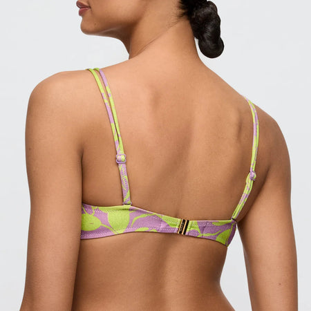 Woman wearing a green and purple patterned bikini top on a plain background