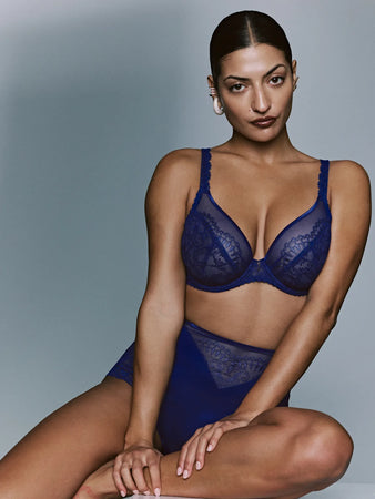 Woman wearing a blue lace lingerie set against a gray background