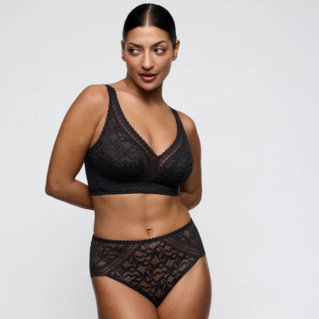 Woman wearing black lace lingerie on a plain background