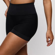 Load image into Gallery viewer, Black high-waisted shorts worn by a person on a plain background
