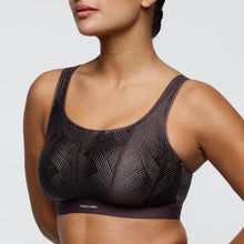 Load image into Gallery viewer, Black patterned sports bra worn by a model on a light gray background
