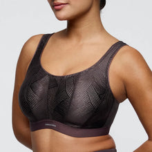 Load image into Gallery viewer, Black patterned sports bra worn by a model on a light gray background
