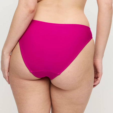 Person wearing bright pink high-waisted underwear on a plain background