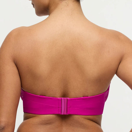 Person wearing a bright pink strapless top on a plain background