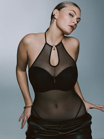 Woman wearing a black sheer top and skirt against a gray background