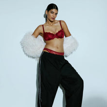Load image into Gallery viewer, Woman wearing a red bralette, black pants with white stripes, and white fluffy sleeves against a light blue background.

