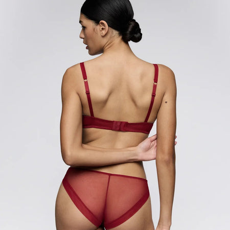 Woman wearing a red lingerie set against a white background