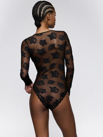 Person wearing a black lace bodysuit on a white background