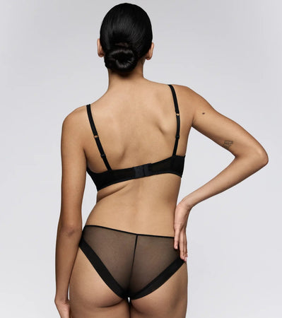 Person wearing a black lingerie set on a plain background