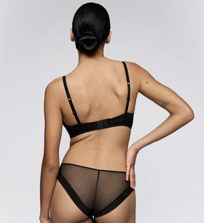Person wearing a black lingerie set on a plain background