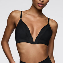 Load image into Gallery viewer, A close-up of a model wearing a black underwire bra with thin adjustable shoulder straps and small gold metal accents at the strap bases, set against a plain light gray background.
