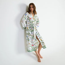 Load image into Gallery viewer, A woman models a white long-sleeve kimono-style robe with a colorful botanical and bird pattern, standing against a plain white wall.
