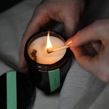 Load image into Gallery viewer, Person lighting a candle with a match, close-up shot.
