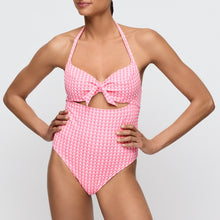Load image into Gallery viewer, Woman wearing a pink checkered swimsuit with a bow detail on a light gray background
