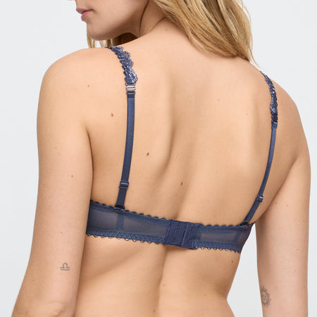 Navy blue lace bra on a model against a white background