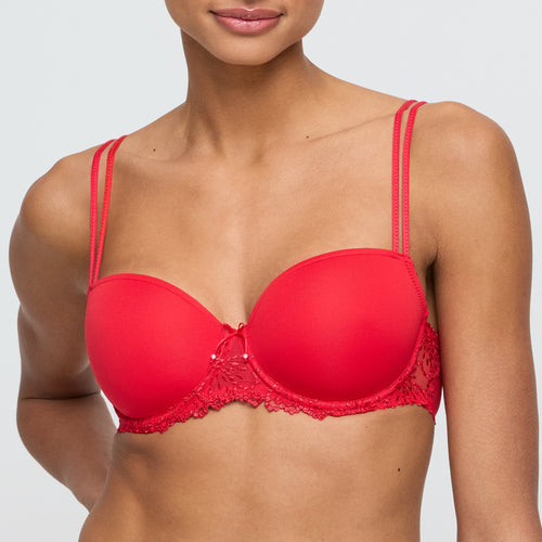Red bra with lace details worn by a model on a plain background