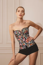 Load image into Gallery viewer, This is a beautiful corset made the French way. It has a square neckline at the front with pearl encrusted embellishment detail around its edges. The clever hidden boning and panelling that draws in the waist and supports the bust. The jolly Parrot pattern on a black ground continues around the back. where there is a centred zip. This is a stunning garment. It is perfect for outwear.
