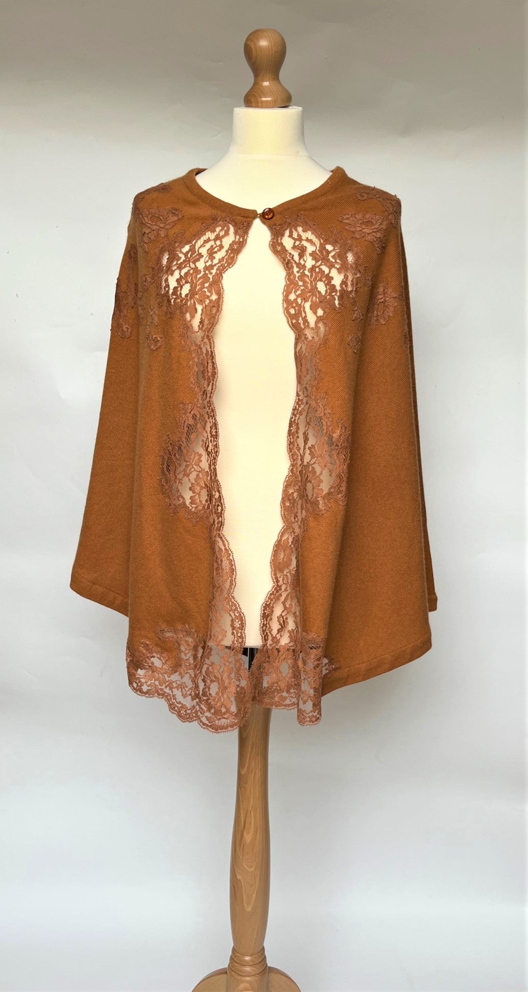 SALE Marjolaine Poncho style Bedjacket in a warm copper shade. Made from 100% pure cashmere it has colour matched appliqué lace inserts at the front, running along the opening edge, finishing beautifully on the corners of the hem edge. There is a one cashmere covered button detail.  Fabric: 100% Cashmere Lace: Leavers-Calais 