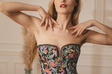 Load image into Gallery viewer, This is a beautiful corset made the French way. It has a square neckline at the front with pearl encrusted embellishment detail around its edges. The clever hidden boning and panelling draw in the waist and supports the bust. The jolly Parrot pattern on a black ground continues around the back. where there is a centred zip. This is a stunning garment. It is perfect for outwear.
